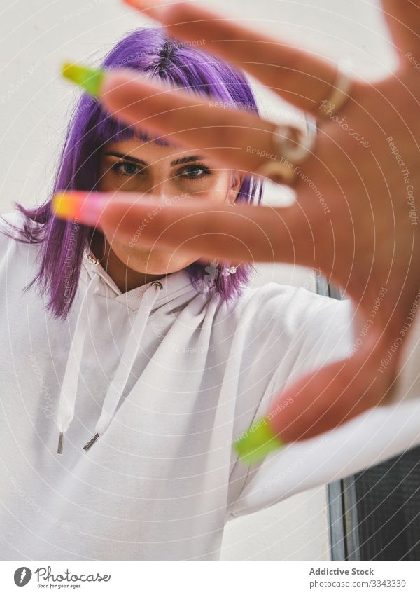 Playful stylish woman covering camera with hand having fun hoodie urban purple gesturing hairstyle finger confident manicure fashion young closing model human
