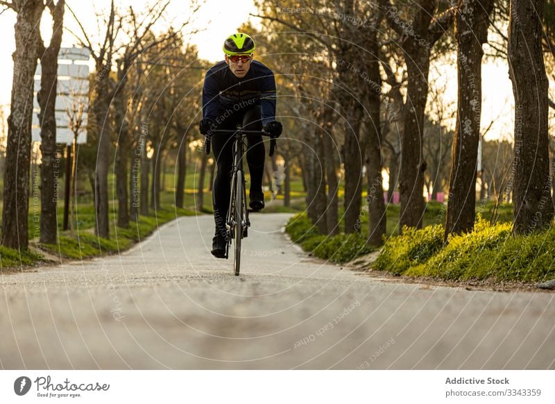 Man cycling in a park race freedom helmet ride speed bicycle bike cyclist exercise fast fitness man person sport adventure healthy lifestyle nature road urban