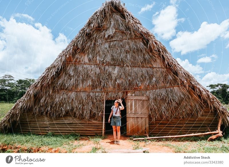 Woman on vacation near old house at countryside woman rural doorway standing thatched roof blue sky summer cloud green grass travel tourism nature young female