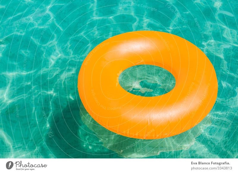 orange inflatable donut on blue water in a swimming pool. Summer Inflatable Water Joy Swimming pool Donut Party Beautiful Float in the water Woman