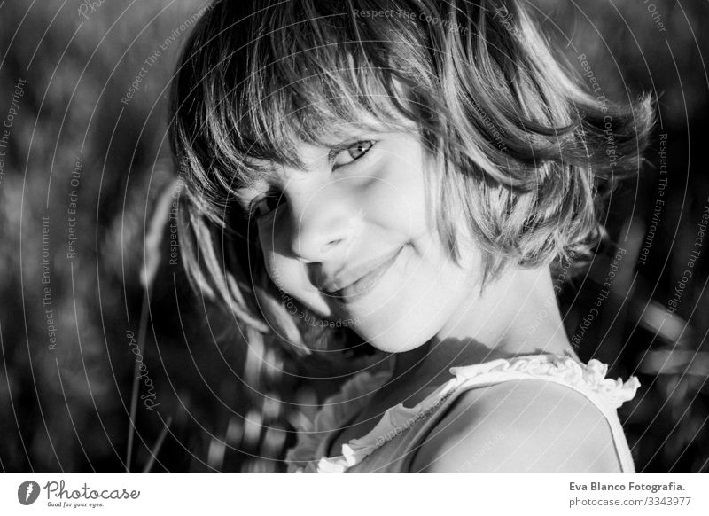 portrait outdoors at sunset of a beautiful kid girl among the flowers. Black and white photography. Innocence and children lifestyle. Summer Smiling heat wave