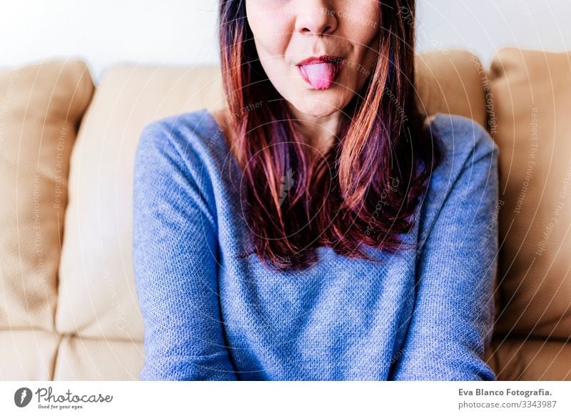 close up portrait of a young woman with her tongue out. Fun at home, indoors Portrait photograph fooling grimacing Smiling Make-up Nice Joy Attractive Fashion
