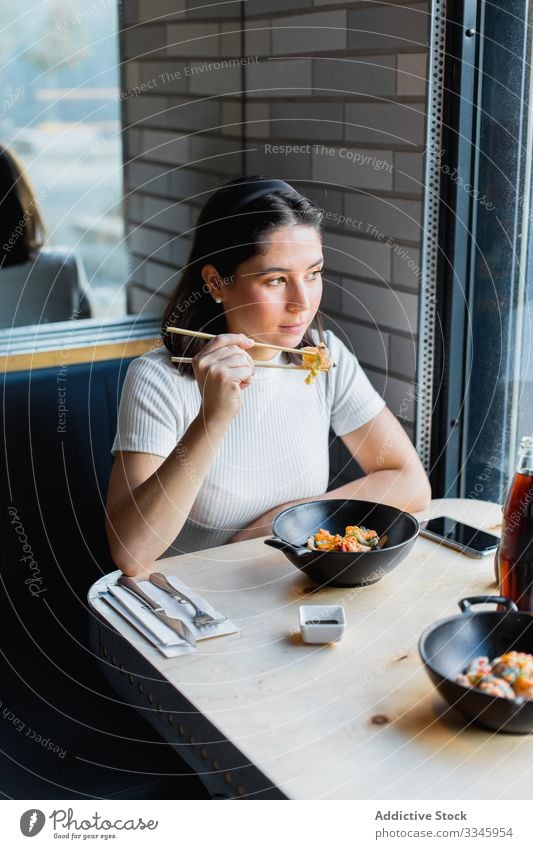 Thoughtful woman with chopstick in hand during lunch in asian cafe chopsticks asian food using eating sitting table female casual vegetable dining restaurant