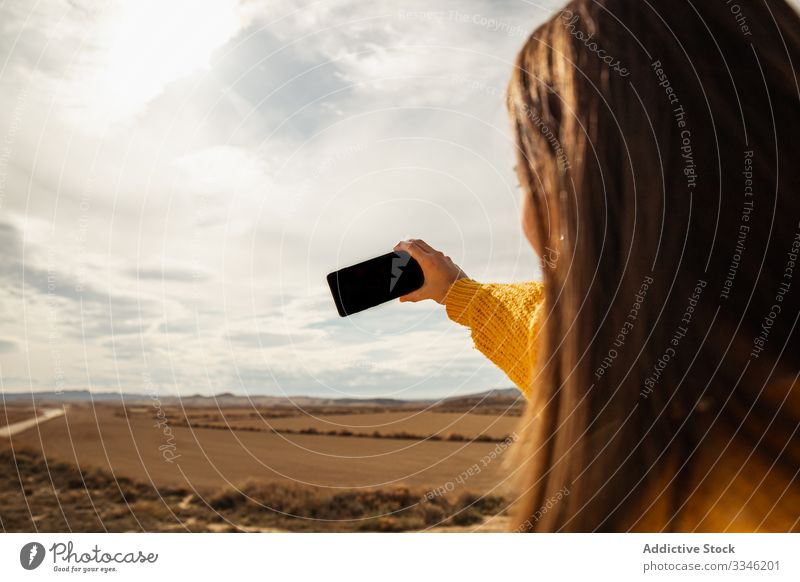 Anonymous female taking selfie on mobile phone woman shooting using smartphone mountain blue sky nature smile enjoy travel vacation casual stylish summer desert