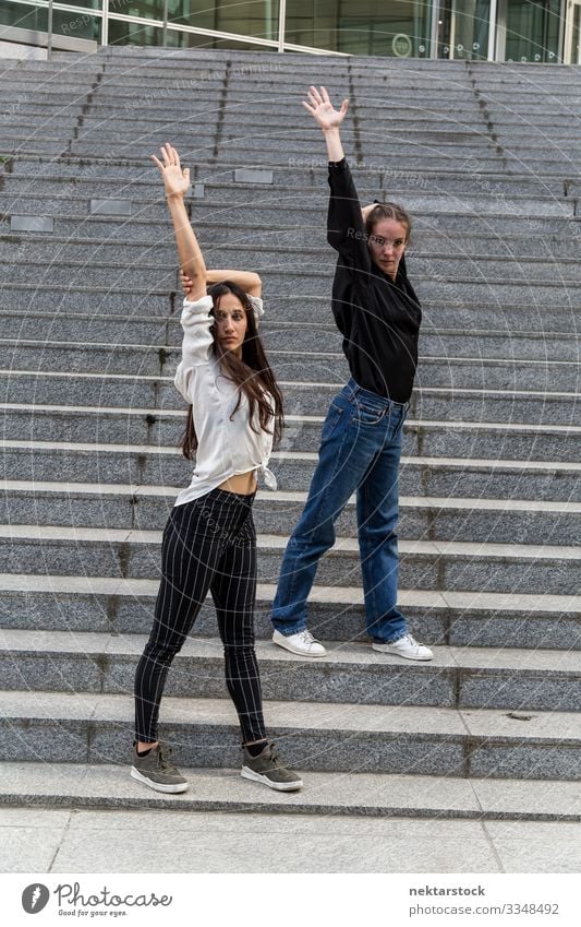 Two Women Posing on Steps with Arms Raised Woman Adults Youth (Young adults) Youth culture Contentment dancing girls steps arms raised staircase dancers