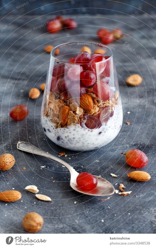 Chia pudding parfait with red grapes and almonds Yoghurt Fruit Dessert Eating Breakfast Diet Spoon Dark Gray White jar chia Bunch of grapes nuts Pudding seed
