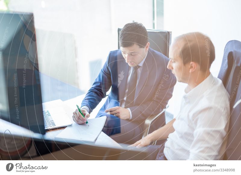 Image of two corporate businessmen discussing a bisiness problem at meeting in modern trading office. Businesspeople sitting at the boardroom and discussing business-plan.