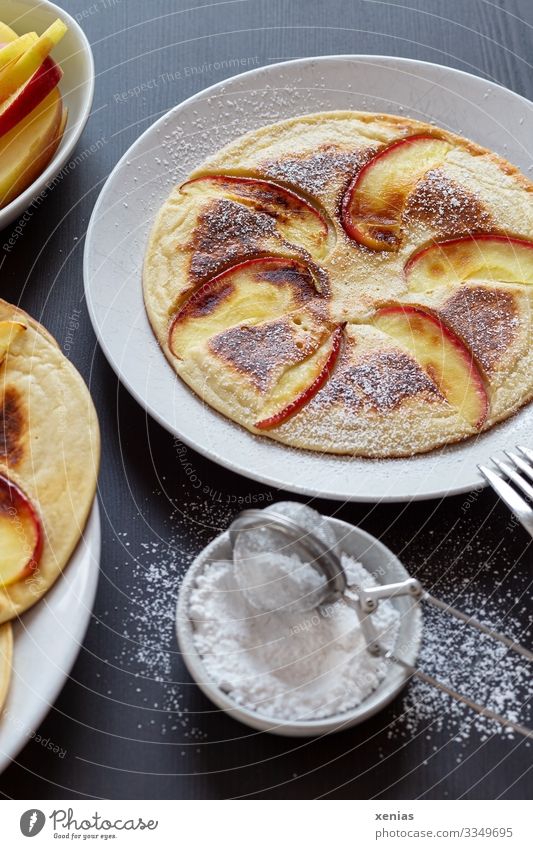 Pancakes with apple and icing sugar on white plate Apple Dough Baked goods Candy Confectioner`s sugar Slice of apple Sugar Nutrition Organic produce Food