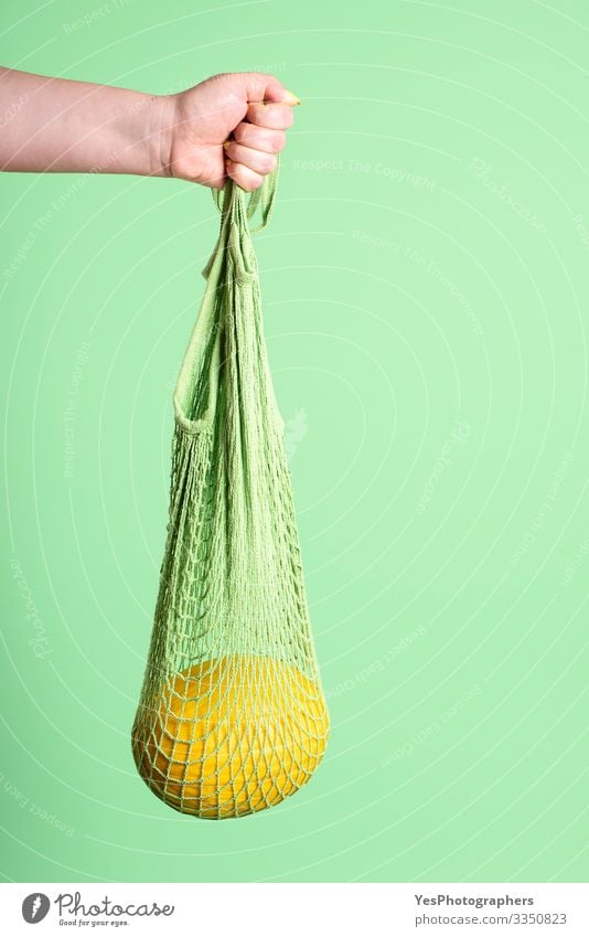 Yellow melon hanging in reusable mesh shopping bag Fruit Dessert Organic produce Diet Shopping Healthy Eating Feminine Hand Green buying fruits colorful