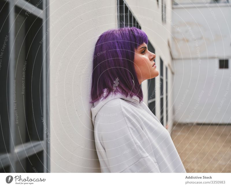 Thoughtful woman with purple hair in white hoodie leaning on wall stylish urban hairstyle confident fashion young dead end thoughtful pensive sad depression