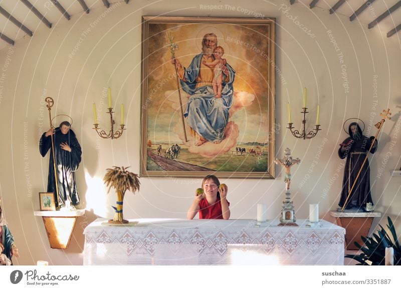 child stands in a chapel behind an altar and plays with apples Child girl Church Chapel Altar Playing nonsense naughty Religion and faith Christianity Belief