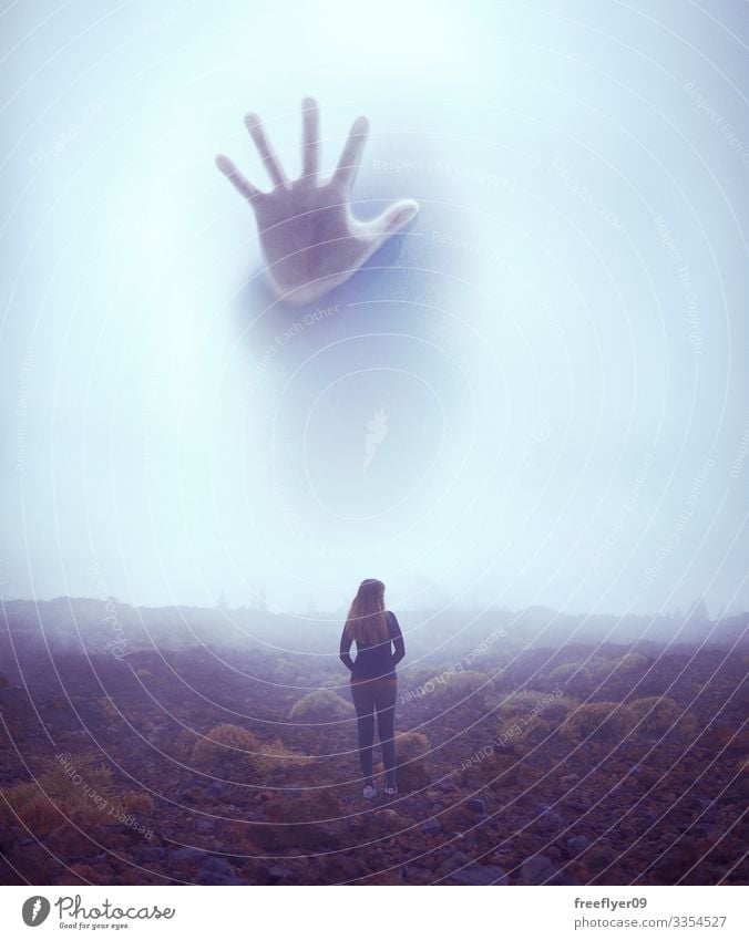 Young woman facing a giant creature that hides on the fog young fear mysterious mystery outdoor vertical tiny monster threat dangerous hand reaching courage