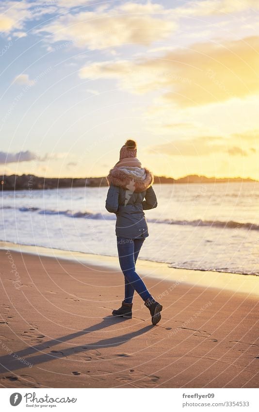 Young woman walking on the beach with winter clothing at sunset in Vigo young backwards vigo female vacation people sand sea autumn fall coastal boots