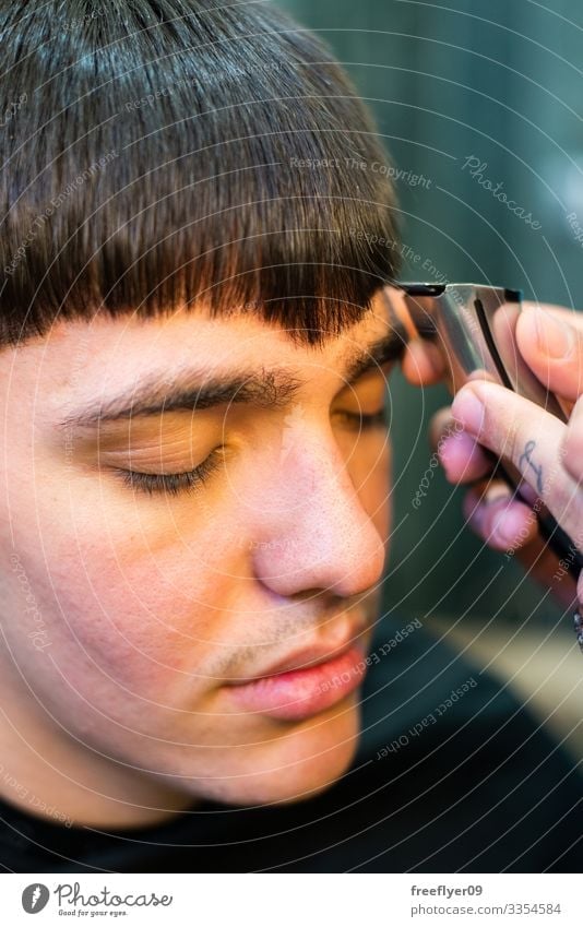 Close up of a working barber man client professional style care hairdresser design adult coiffure young beautician hand haircut comb caucasian male beauty