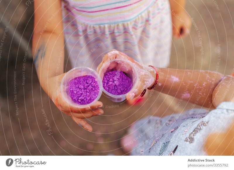 Little girls showing cups with paint in park festival summer together friend celebration little kid child season pigment dye powder demonstrate holiday