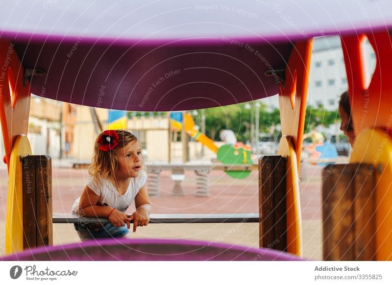 Funny girl playing on playground railing peek out fun rest kid child childhood relax lifestyle curious imagination fantasy cheerful happy joy summer daytime