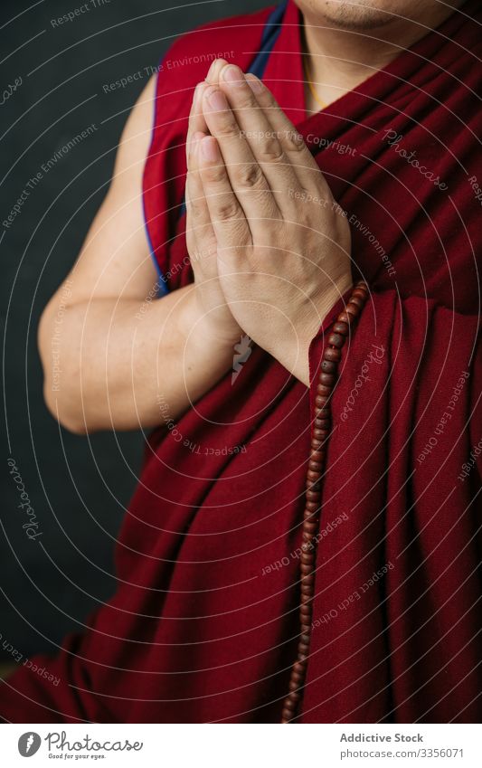 Praying Buddhist monk with folded hands buddhist gesture pray religion mudra namaste symbol traditional beads rosary tibet red culture spirituality faith belief