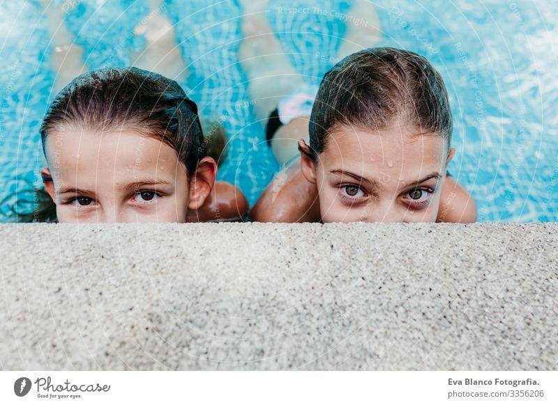 two beautiful teenager girls floating in a pool and looking at the camera. Fun and summer lifestyle Action Swimming pool Exterior shot Youth (Young adults) Girl