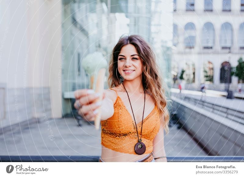 Beautiful young caucasian woman eating mint ice cream at the city street on a sunny day. Happy face smiling. Urban and summer lifestyle Day Street Woman Sunbeam