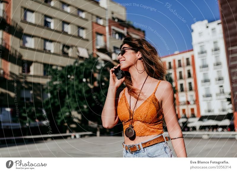 Beautiful young caucasian woman walking at the city street on a sunny day. Talking on mobile phone. Happy face smiling. Urban lifestyle Day Street Woman Sunbeam