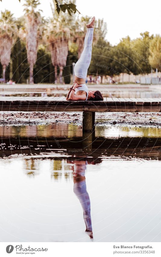 young beautiful asian woman doing yoga in a park. Sitting on the bridge with reflection on the water lake. Yoga and healthy lifestyle concept Practice