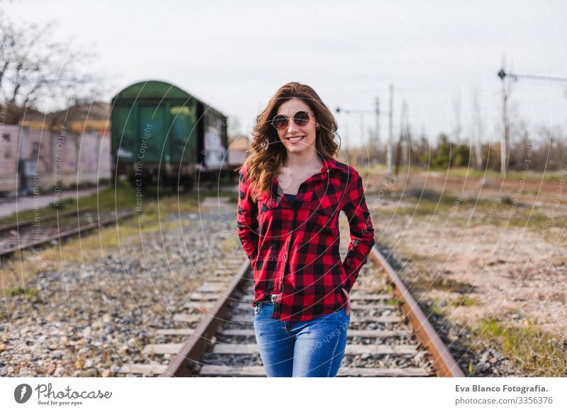 young beautiful woman wearing casual clothes, walking by the railway and smiling. Outdoors lifestyle. Travel concept. City Exterior shot Feminine Fashion