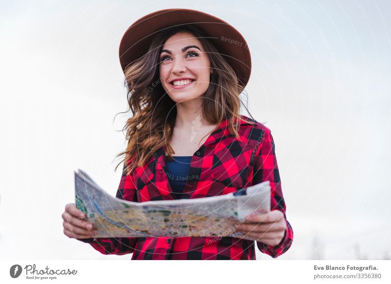 close up portrait of a young beautiful woman wearing casual clothes, looking a map, wearing a modern hipster hat. Outdoors fun and lifestyle. Travel concept.