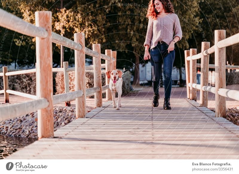 young woman and her dog outdoors walking by a wood bridge in a park with a lake. sunny day, autumn season Portrait photograph Woman Dog Park