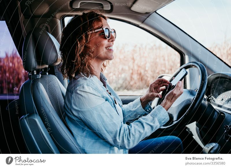 young beautiful woman using mobile phone in a car. travel concept Cellphone Technology Woman Youth (Young adults) Driving Car Sunbeam Sunglasses