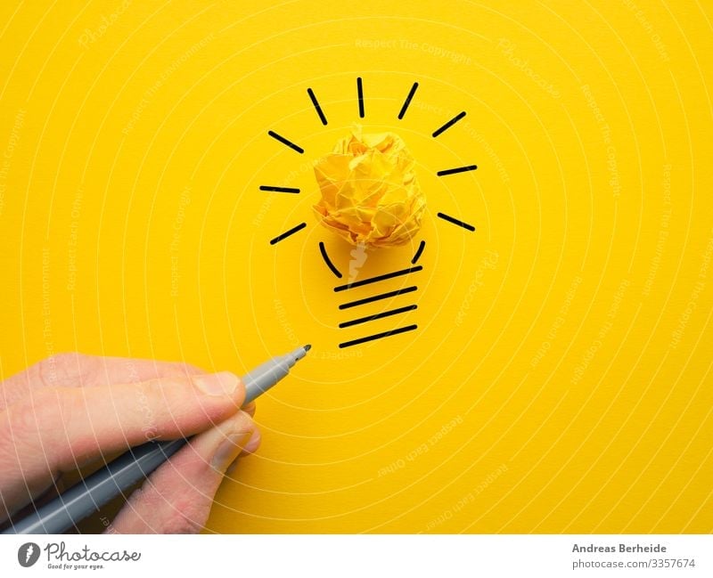 Yellow crumpled paperball as lightbulb hand idea lamp energy concept drawing businessman power electricity bright innovation symbol creativity ideas finger