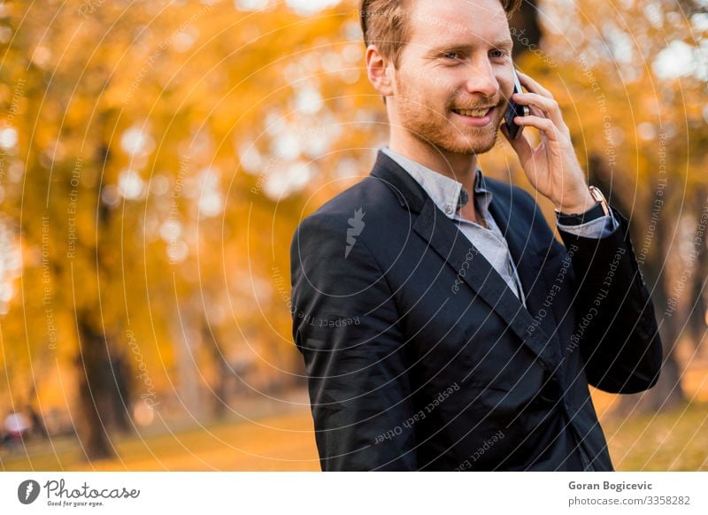 Young man with mobile phone in the autumn park Lifestyle Style To talk Telephone PDA Technology Human being Youth (Young adults) Man Adults 1 18 - 30 years