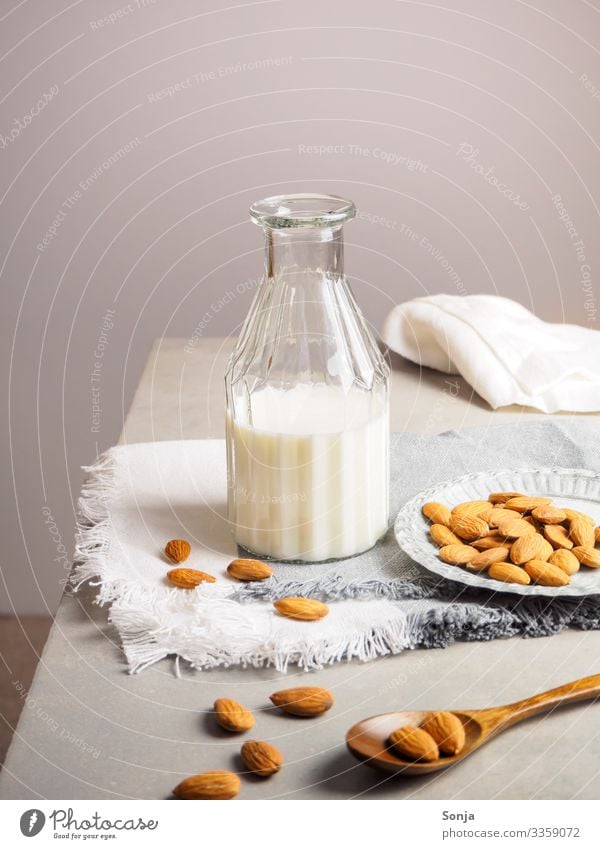 Almond milk in a glass bottle on a table Food Nutrition Breakfast Organic produce Vegetarian diet Diet Beverage Milk Bottle Glass Lifestyle Healthy