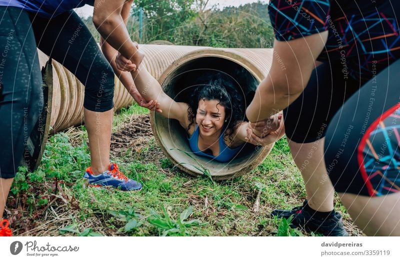 Woman in obstacle course going through pipe Lifestyle Sports Human being Adults Group Tube Authentic Strong Effort Competition Teamwork pulling