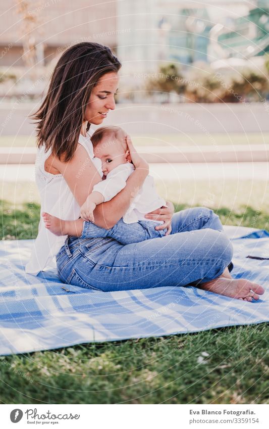 young mother playing breast feeding her baby girl outdoors in a park, happy family concept. love mother daughter Mother Baby Appease Milk Eating Child Parenting