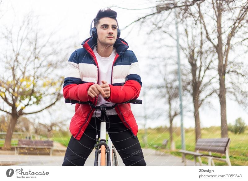 Handsome hipster young man enjoying a bicycle ride and using a smartphone while listening music by headphones street bike people male person walking earphones
