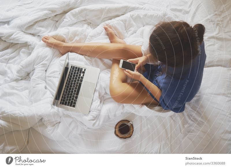 Young woman at home in her bed and checking her smartphone Coffee Beautiful Life Relaxation Reading Bedroom Work and employment Workplace Computer Notebook