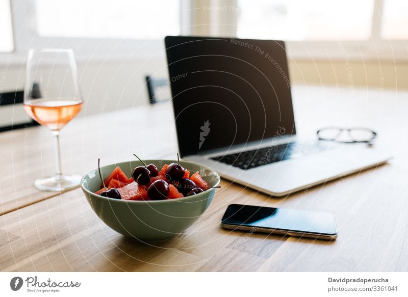 Comfortable work space with devices and fresh berries on table laptop freelance relax wine workspace fruit bowl break berry chill alcohol smartphone mobile