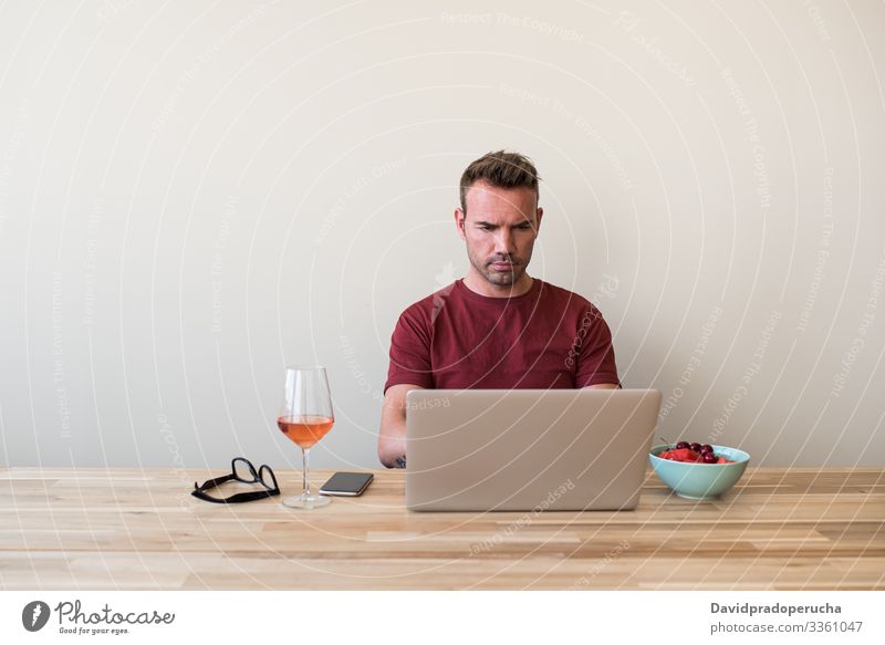 ale freelancer using laptop at home man kitchen relax table wine chill surfing browsing typing weekend alcohol alone beverage refreshment remote dining room