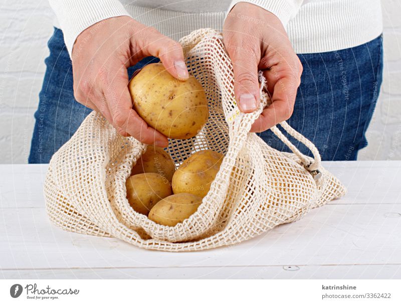 Woman put fresh potatoes in a textile bag Food Vegetable Lifestyle Shopping Adults Hand Environment Plastic Free Natural White Zero waste Conceptual design