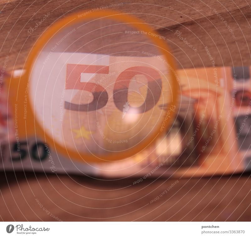 Magnifying glass magnifies 50 Euro note Sign Digits and numbers Money Euro symbol Paying Shopping Bank note Testing & Control Authentic original Fraud Wood