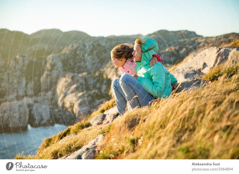 Two little girls play on rocky northern seashore. Action Adventure Recklessness Friendliness Cheerful Infancy Child Dawn Europe Fjord Friendship Joy Happiness