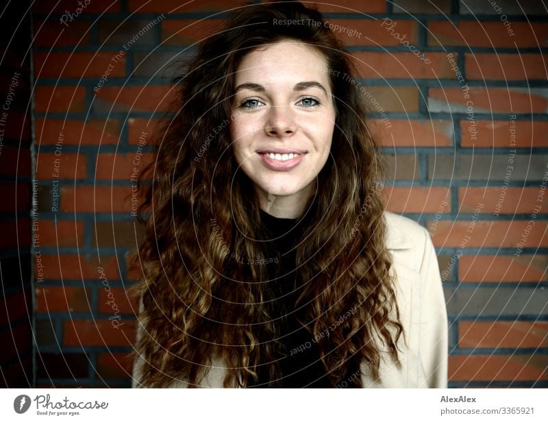 Portrait of a young woman in front of a brick wall Lifestyle Style Joy already Young woman Youth (Young adults) Face 18 - 30 years Adults Coat brunette