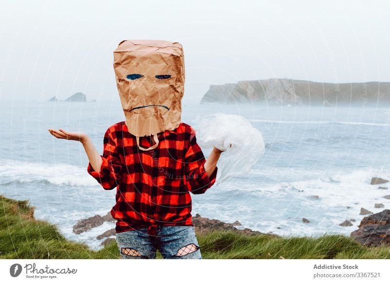 Person with paper bag on head holding plastic package ecology concept disapproval dislike disagree environment person gesture sign nature pollution problem