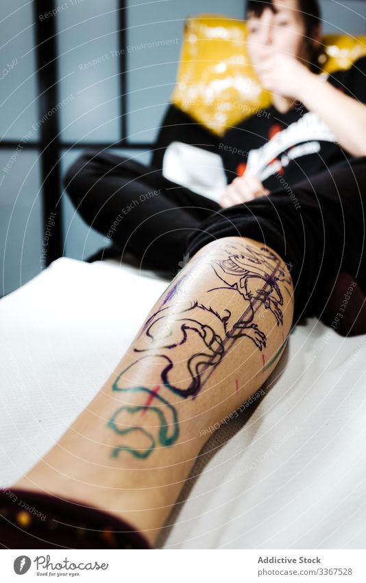 Female with transferred tattoo on leg lying in salon woman image stencil sketch client cosmetology skin cosmetic treatment color ink drawing design master art