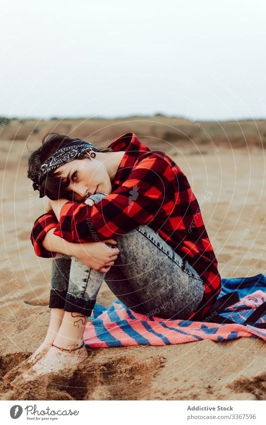 Thoughtful hipster woman sitting on sandy beach pensive serious young relax thoughtful sea casual female ocean observation think red nature travel coast seaside