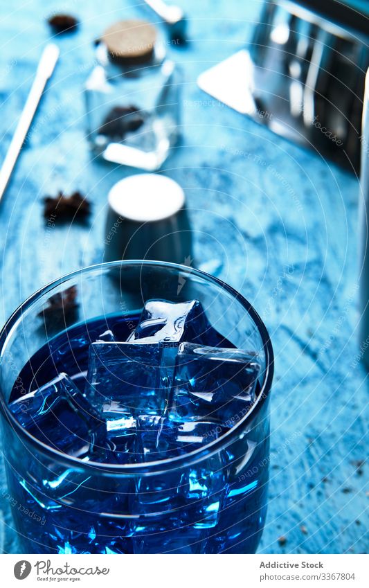 Blue drink and bartender tools on table blue cocktail ice cube barman equipment glass beverage alcohol cold liquid party juice refreshment cool freshness color