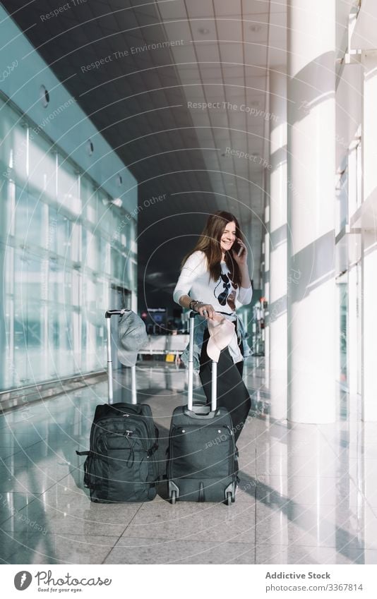 Calm woman using phone in airport talking surfing baggage vacation departure arrival adventure female wait smartphone delay public destination browsing explore