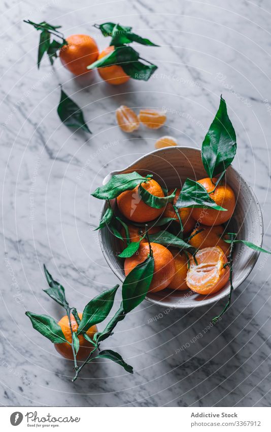 Orange tangerines in ceramic ornamental bowl on marble table sophisticated fruit healthy classic composition still life art fresh juicy organic green tasty food