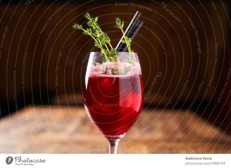 Stylish served alcohol cocktail with rosemary drink beverage bar mixed berry red tube restaurant glass refreshment liquid cold herb evening colorful pub