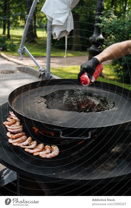 Crop male pouring oil on pan man cook dish chef shrimp oven paella fried hot marketplace preparation meal heat flame cookery mixed fresh seafood recipe meat